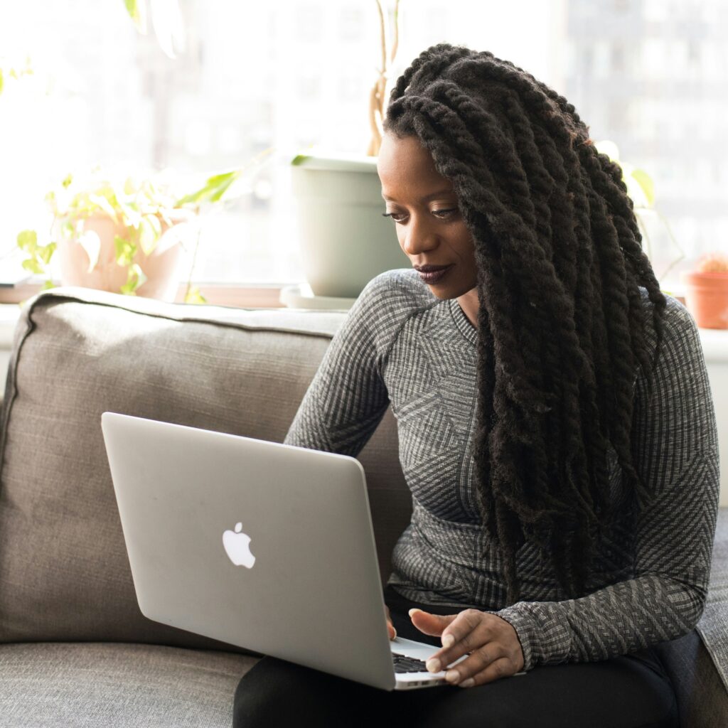 woman sitten on the sofa with a laptop on her lap