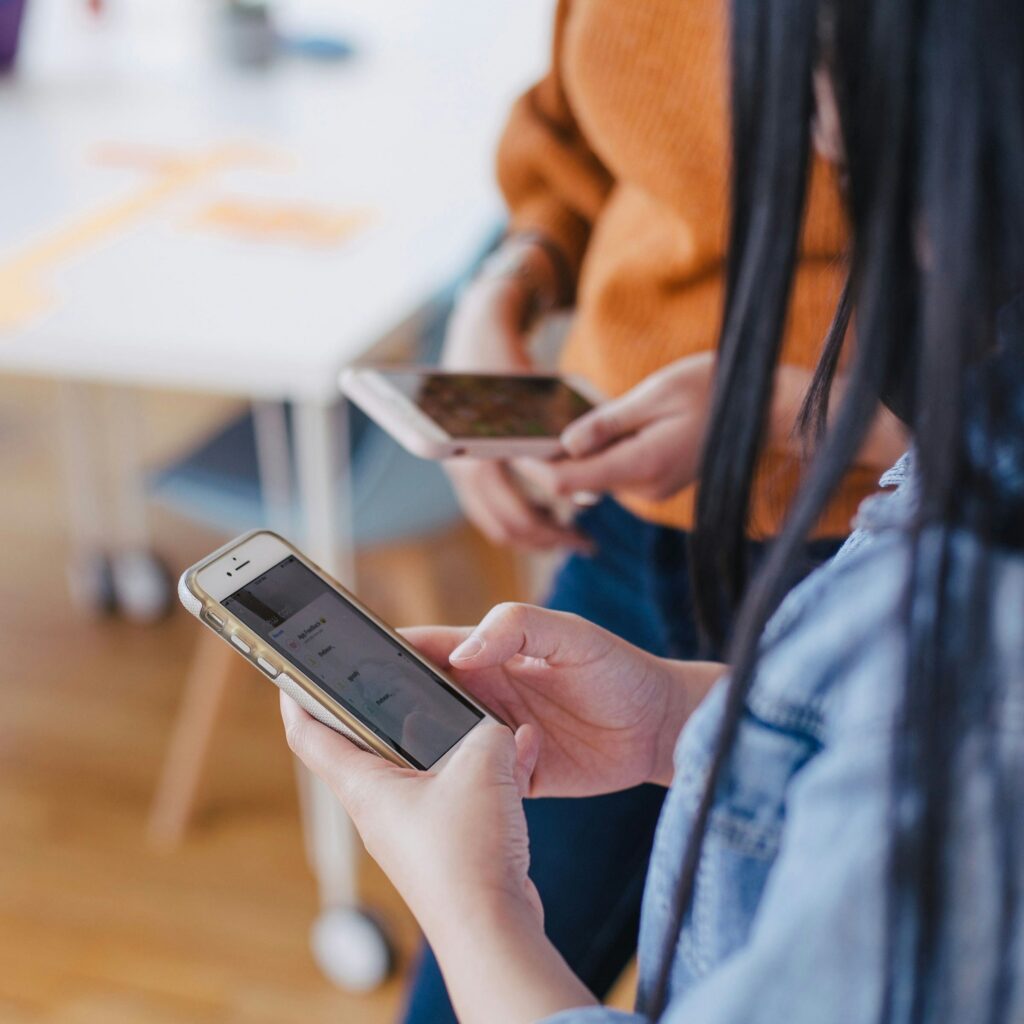 photo of two women standing with a mobile phone in their hands